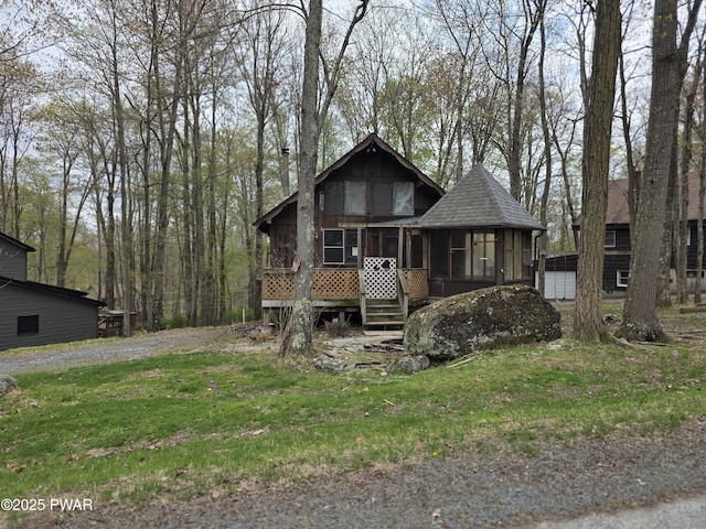 chalet / cabin with a shingled roof, a sunroom, a front yard, and a chimney
