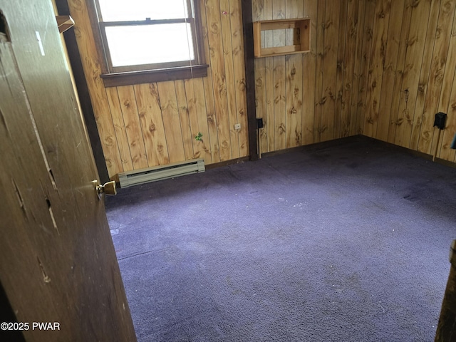 carpeted spare room with baseboards, baseboard heating, and wood walls