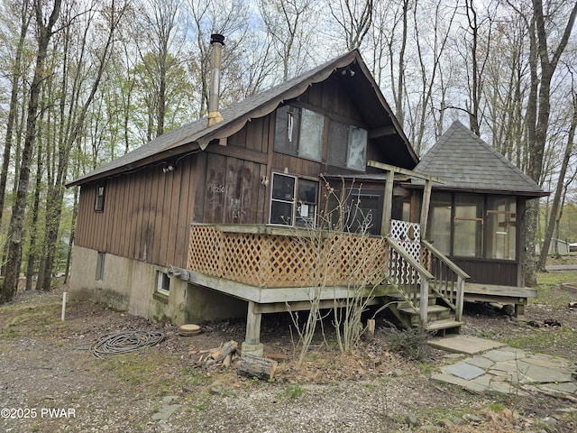 back of house with a sunroom and a shingled roof