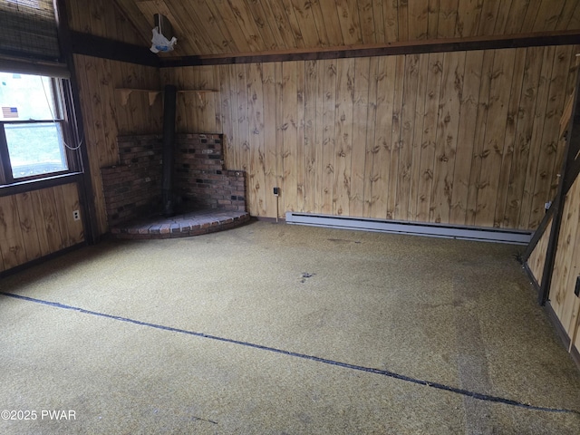 carpeted spare room with wood walls, wood ceiling, a baseboard radiator, and a wood stove