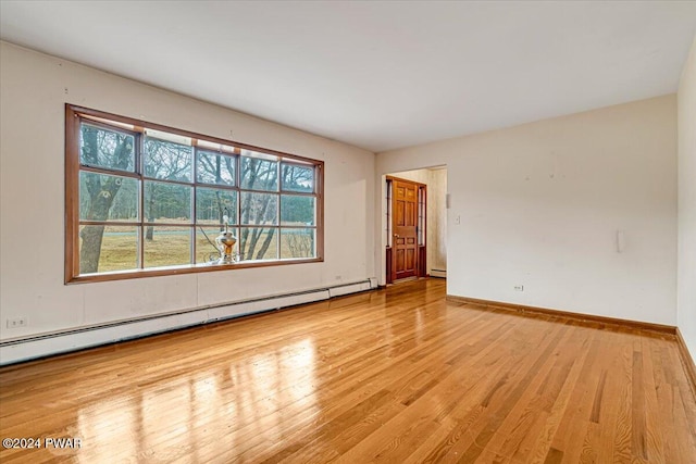 unfurnished room featuring baseboard heating and light hardwood / wood-style flooring