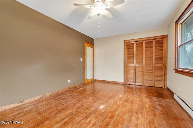 unfurnished bedroom with ceiling fan, a closet, light hardwood / wood-style floors, and a baseboard radiator