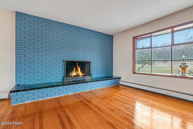 unfurnished living room featuring a fireplace, light hardwood / wood-style flooring, and baseboard heating