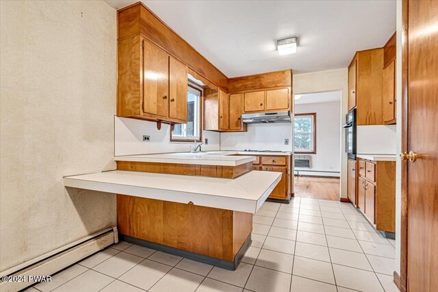 kitchen with baseboard heating, kitchen peninsula, black oven, and light tile patterned floors