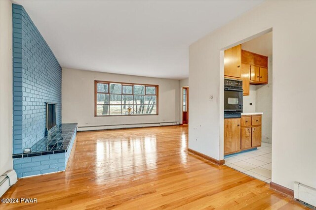 unfurnished living room with a fireplace, light wood-type flooring, and a baseboard radiator