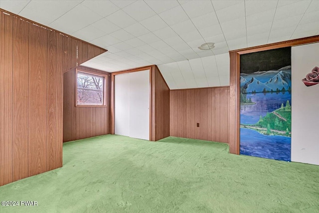 bonus room featuring light colored carpet and wooden walls