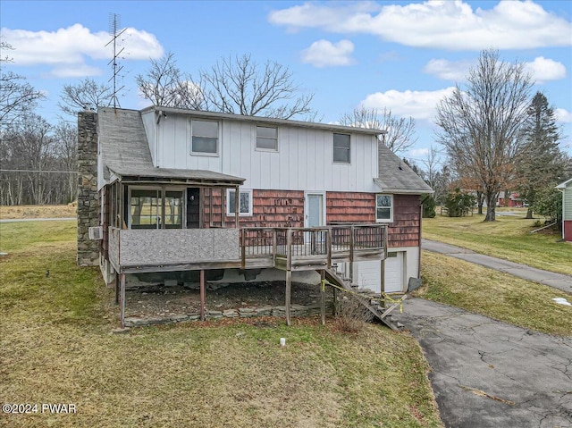 back of property featuring a wooden deck, a yard, and a garage