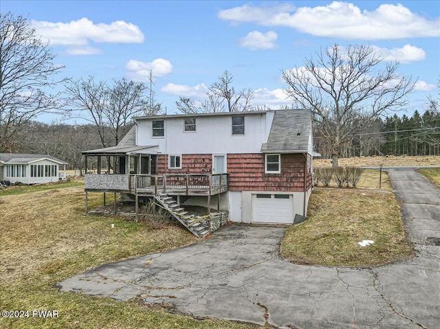 rear view of house with a wooden deck, a yard, and a garage