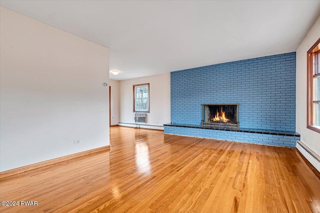 unfurnished living room with a brick fireplace, light hardwood / wood-style floors, and a baseboard heating unit