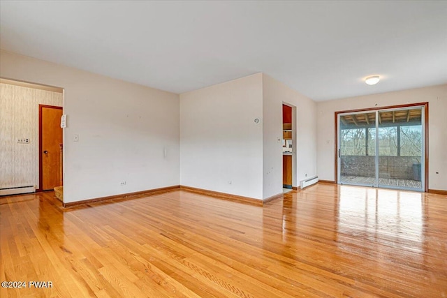 empty room with light hardwood / wood-style flooring and baseboard heating