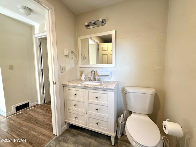 bathroom with hardwood / wood-style floors, vanity, and toilet