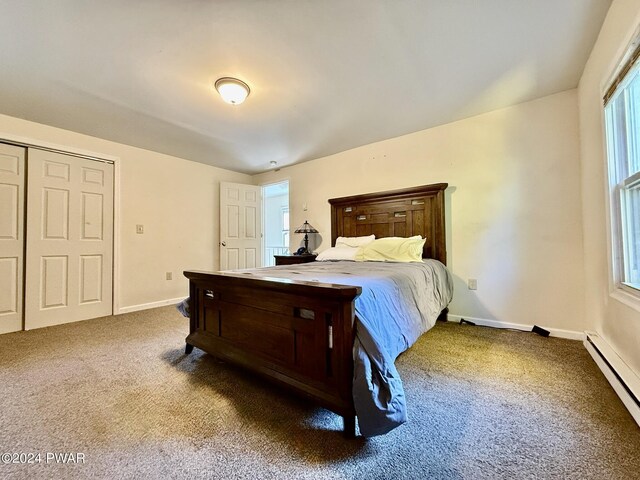 bedroom with multiple windows, a closet, dark carpet, and baseboard heating