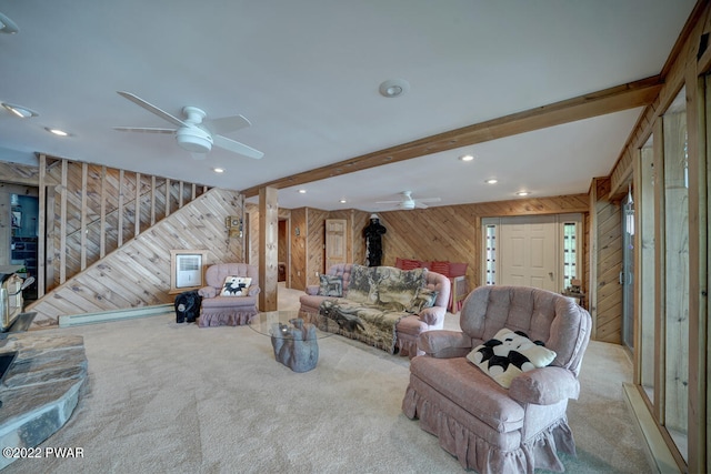 living room featuring beamed ceiling, ceiling fan, light carpet, and wooden walls