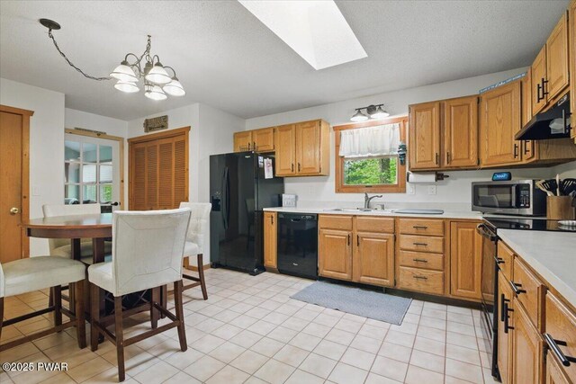 173 Paper Birch S, Tafton, PA 18464 - kitchen with black appliances, under cabinet range hood, light countertops, a chandelier, and a skylight
