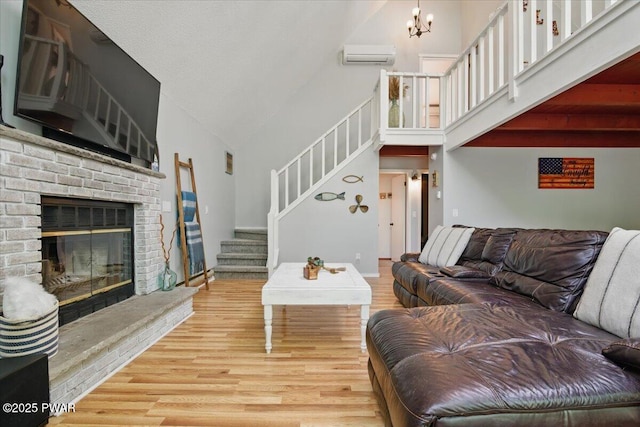 173 Paper Birch S, Tafton, PA 18464 - living area with high vaulted ceiling, stairs, a wall unit AC, wood finished floors, and a brick fireplace