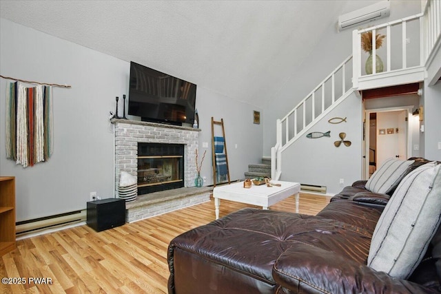173 Paper Birch S, Tafton, PA 18464 - living area featuring a wall mounted air conditioner, a baseboard radiator, stairs, wood finished floors, and high vaulted ceiling