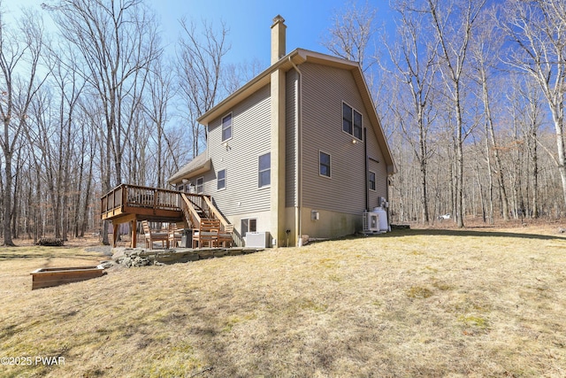 back of house featuring stairway, a wooden deck, a yard, central AC, and a chimney