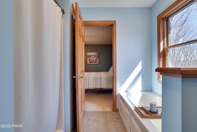 ensuite bathroom featuring a garden tub, a shower with curtain, tile patterned floors, and ensuite bathroom