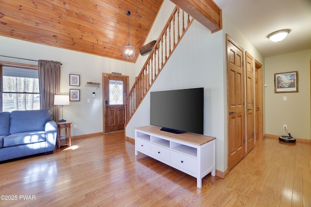 living room featuring stairway, baseboards, lofted ceiling, wooden ceiling, and light wood-type flooring