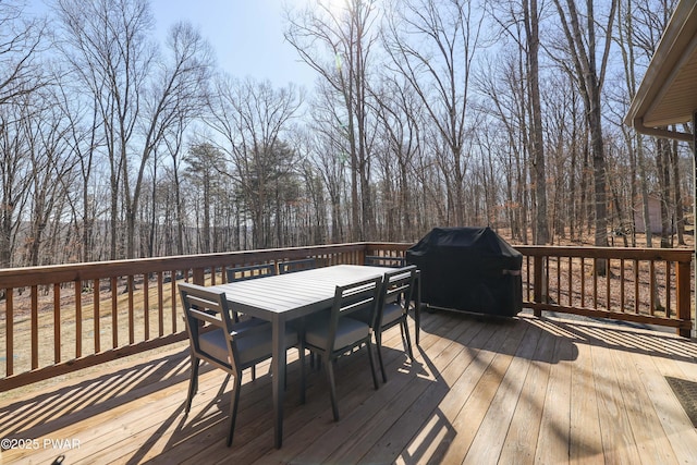 wooden terrace featuring a grill and outdoor dining space