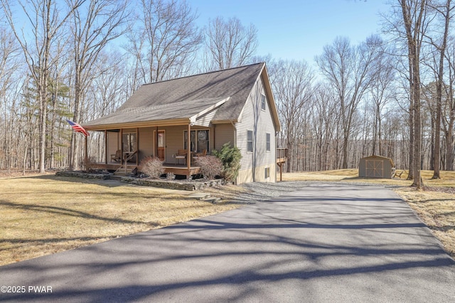 view of front of house featuring driveway, a porch, an outdoor structure, a front lawn, and a storage unit