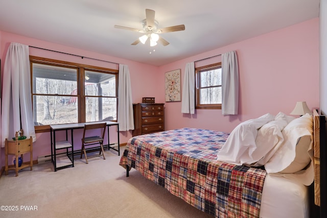 bedroom featuring light colored carpet, baseboards, baseboard heating, and ceiling fan