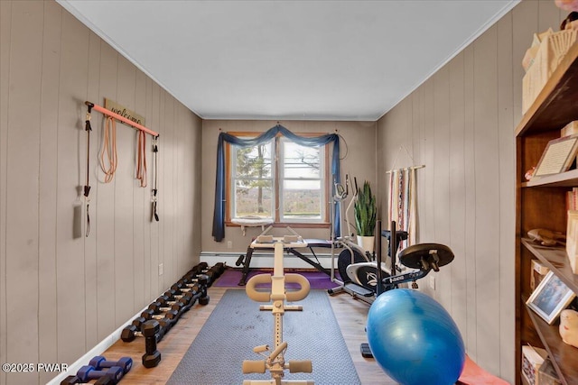 exercise room with wood walls, ornamental molding, and wood finished floors