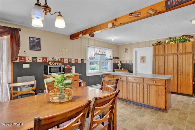 kitchen featuring a kitchen island, stone finish flooring, beam ceiling, light countertops, and stainless steel microwave