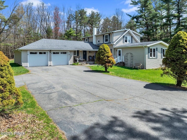 traditional home featuring a garage, a chimney, driveway, and a front yard