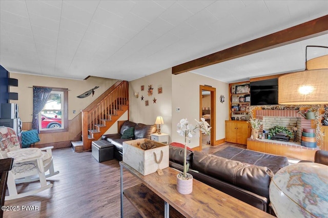 living room with wainscoting, wood finished floors, a fireplace, beamed ceiling, and stairway