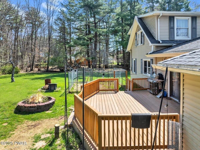 wooden terrace with a lawn, a fire pit, fence, and grilling area