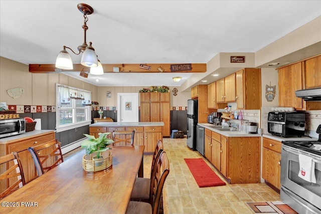 kitchen featuring appliances with stainless steel finishes, a sink, light countertops, under cabinet range hood, and a kitchen island