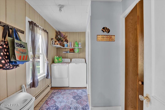 laundry area featuring wooden walls, separate washer and dryer, laundry area, and a baseboard heating unit