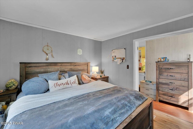 bedroom with ornamental molding and wood finished floors