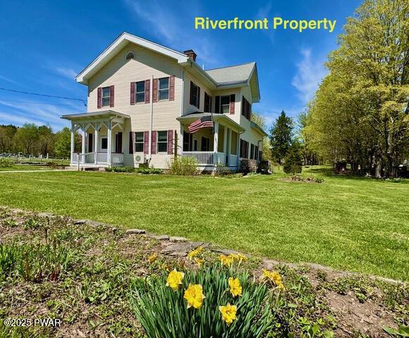 rear view of property with a lawn, a chimney, and a porch