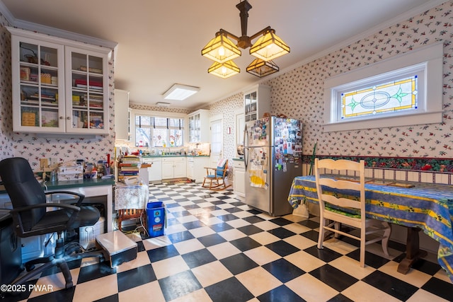 kitchen with stainless steel fridge, white cabinetry, crown molding, and hanging light fixtures