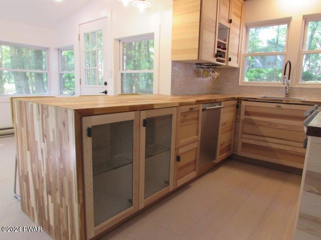 kitchen featuring sink, light brown cabinets, wooden counters, backsplash, and vaulted ceiling