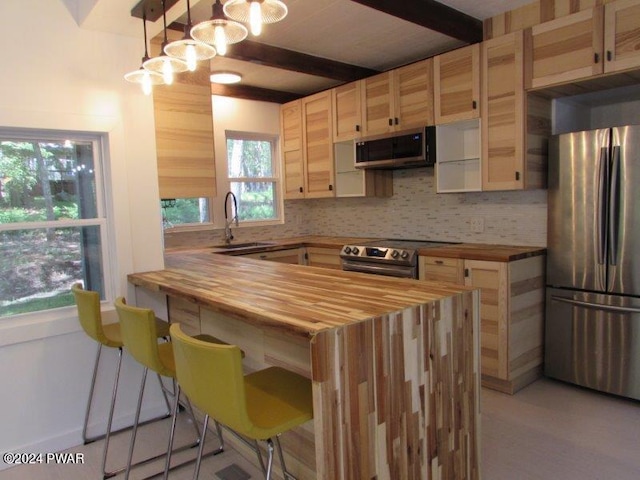 kitchen featuring wood counters, backsplash, sink, appliances with stainless steel finishes, and decorative light fixtures