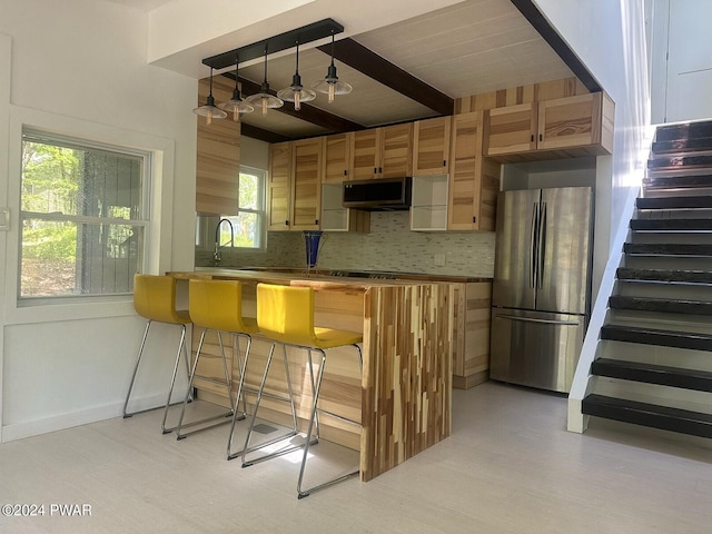 kitchen with pendant lighting, a breakfast bar, backsplash, appliances with stainless steel finishes, and kitchen peninsula