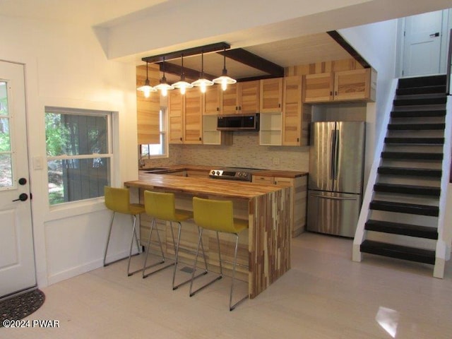 kitchen with kitchen peninsula, appliances with stainless steel finishes, backsplash, pendant lighting, and butcher block countertops