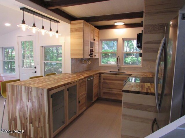 kitchen featuring wooden counters, tasteful backsplash, stainless steel appliances, sink, and hanging light fixtures