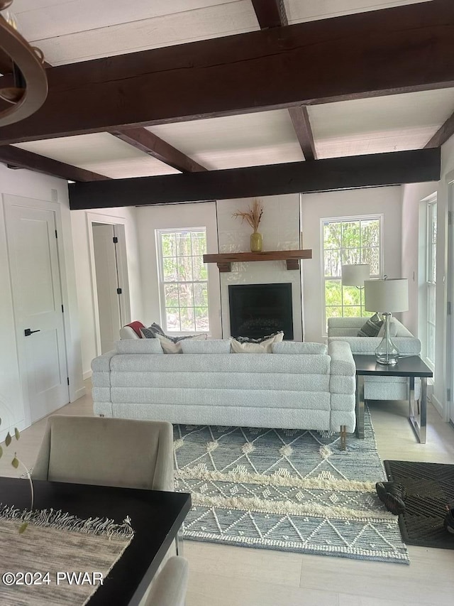 living room featuring a large fireplace, a healthy amount of sunlight, and beamed ceiling