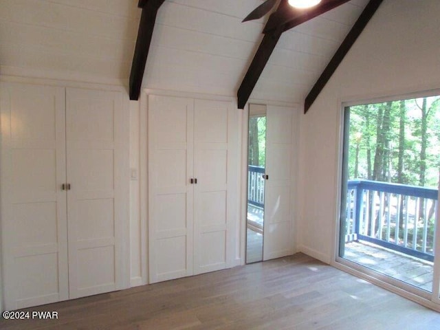 unfurnished bedroom featuring access to exterior, vaulted ceiling with beams, and light hardwood / wood-style flooring