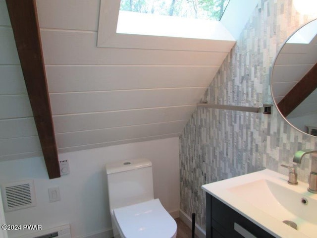 bathroom featuring vanity, toilet, and lofted ceiling