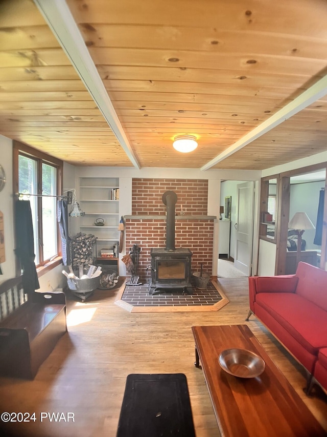 living room featuring beamed ceiling, a wood stove, wood ceiling, and hardwood / wood-style flooring