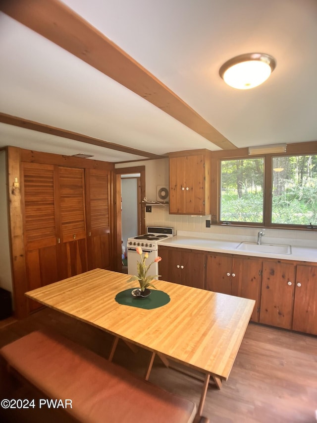 kitchen with decorative backsplash, white gas range oven, light hardwood / wood-style flooring, and sink