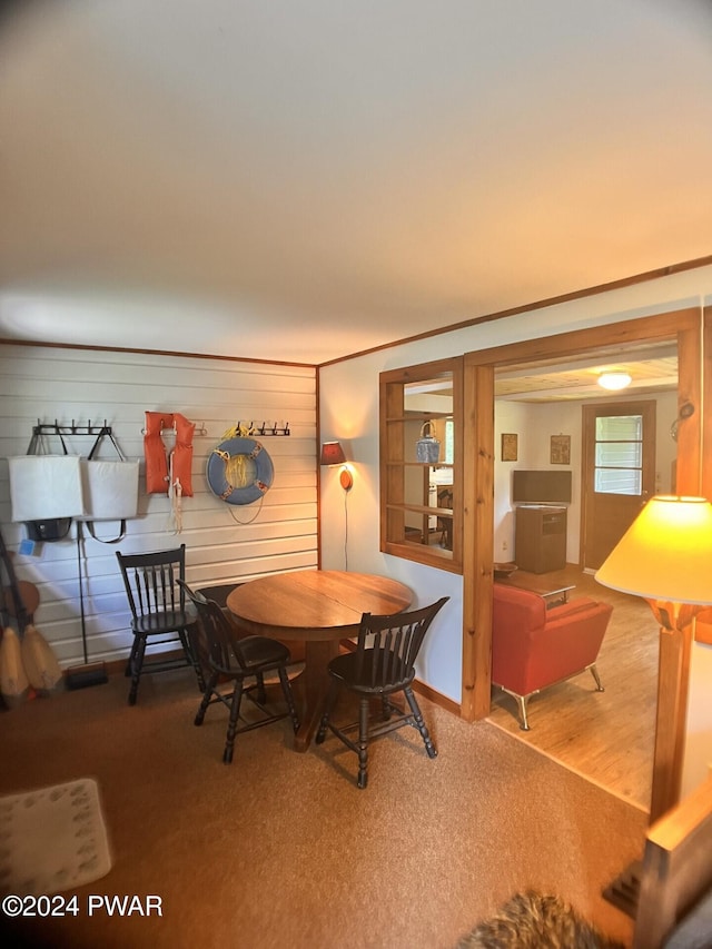 dining space featuring wooden walls and carpet floors