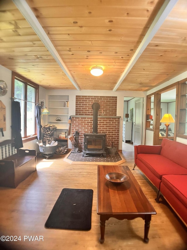 living room featuring beamed ceiling, a wood stove, hardwood / wood-style floors, and wooden ceiling