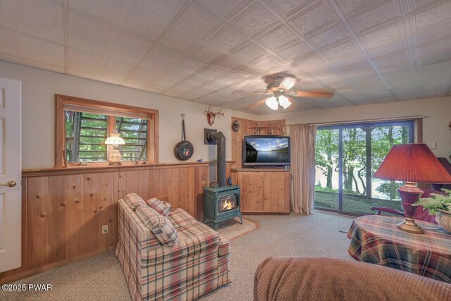 37 Rockpoint Ct, Lake Ariel, PA 18436 - carpeted living room featuring a wood stove, a wainscoted wall, a ceiling fan, and wood walls