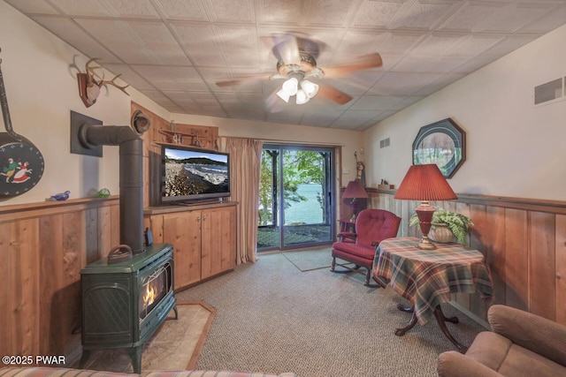 37 Rockpoint Ct, Lake Ariel, PA 18436 - sitting room featuring ceiling fan, light colored carpet, a wood stove, wainscoting, and wood walls